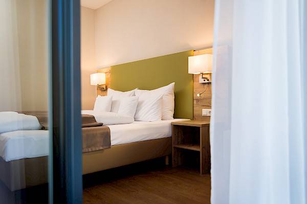 Blick in gemütlich beleuchtetes Hotelzimmer durch offene Balkontüre