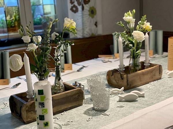 Tischdekoration einer Taufe mit Blumen, Kerzen und Holzschalen